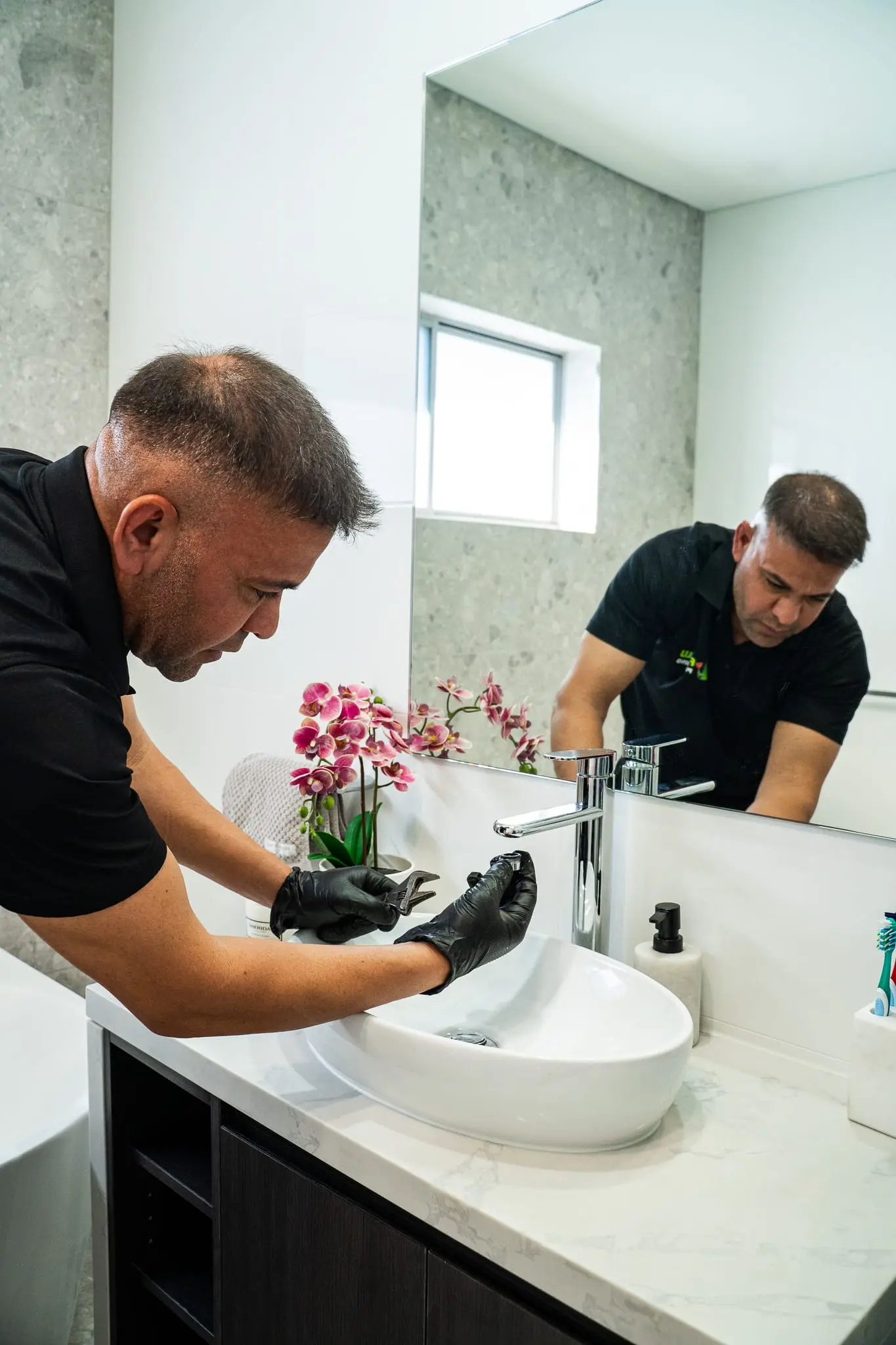 Mr Flow plumber repairing a vanity basin tap in a modern bathroom