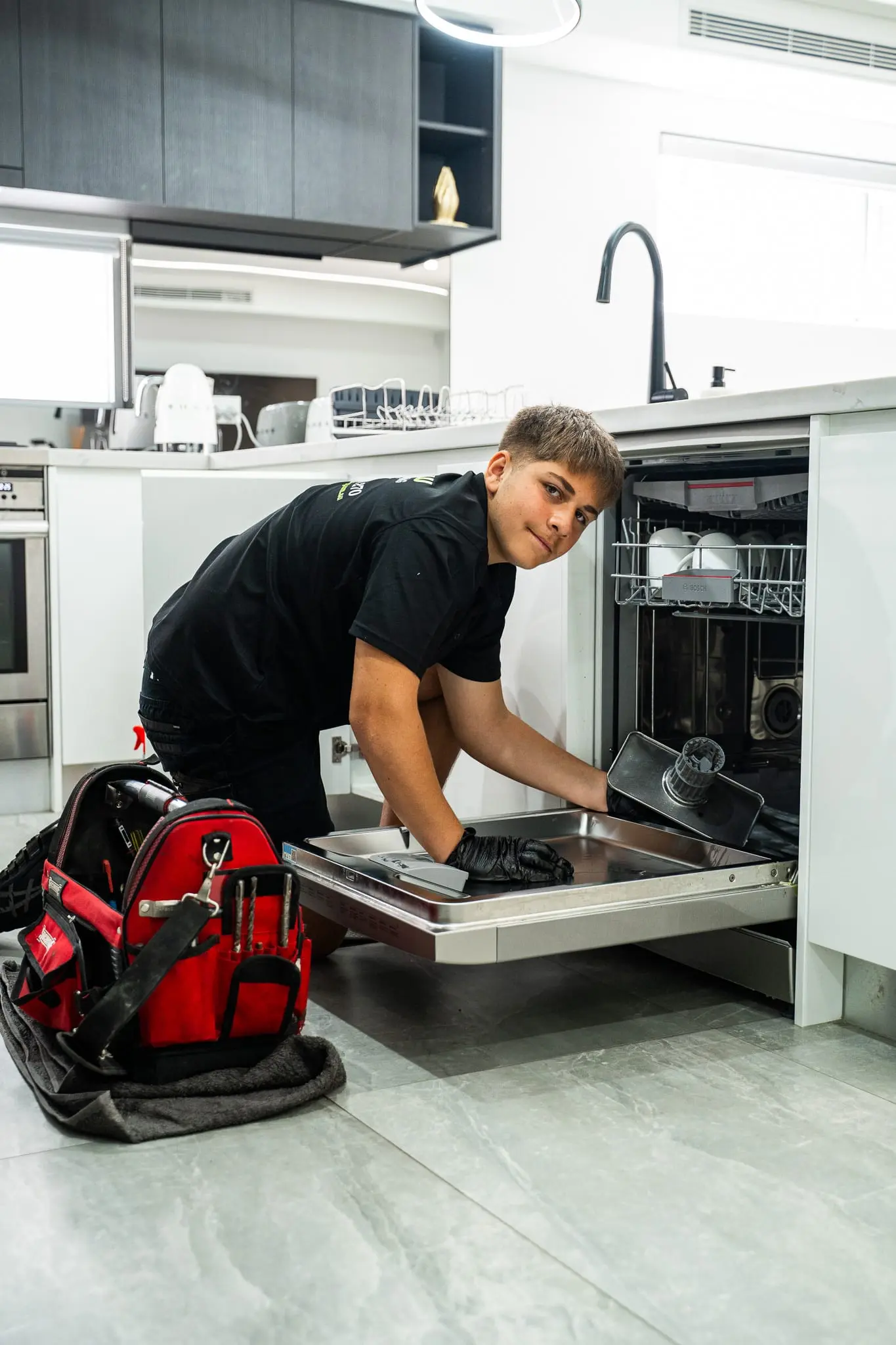 Mr Flow plumber connecting a dishwasher in a modern kitchen
