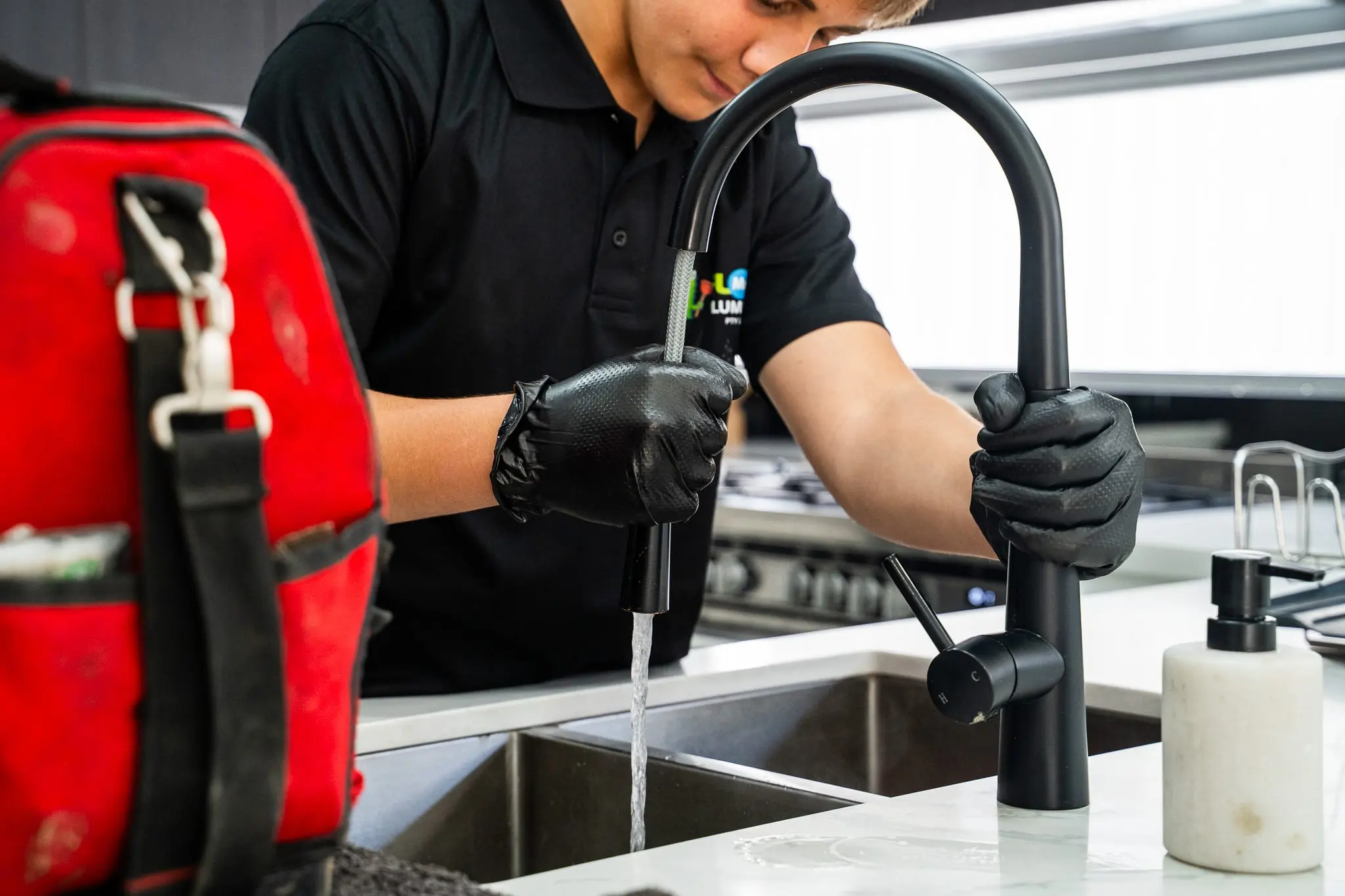 Black gooseneck kitchen mixer running water after a repair