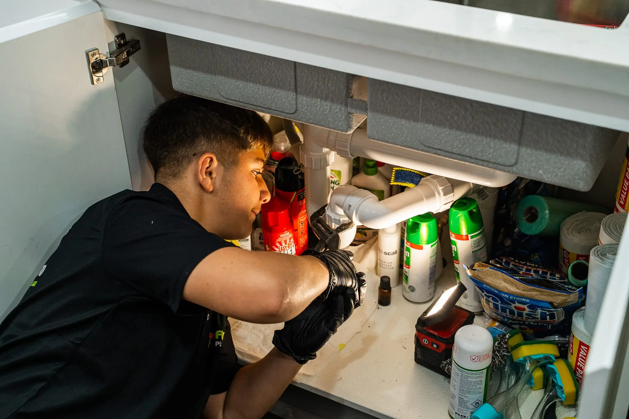 Mr Flow plumber checking the waste pipes under a kitchen sink