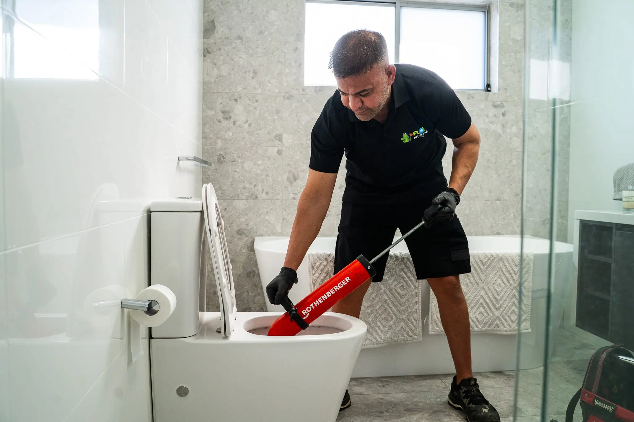 Mr Flow plumber clearing a blocked toilet with a professional plunger
