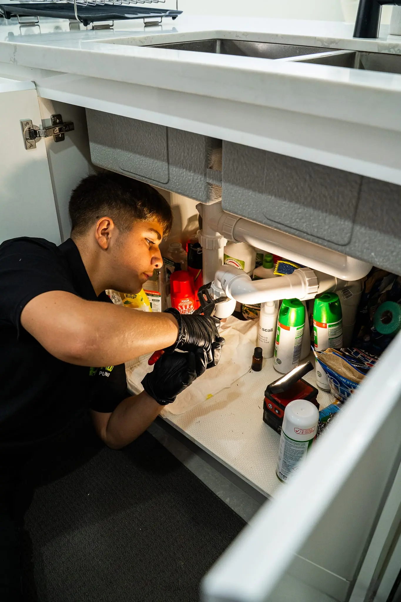 Mr Flow plumber working in the cupboard under a kitchen sink